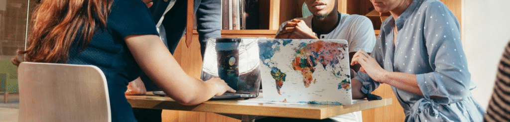 Gruppe von Menschen sitzt mit Laptops am Tisch